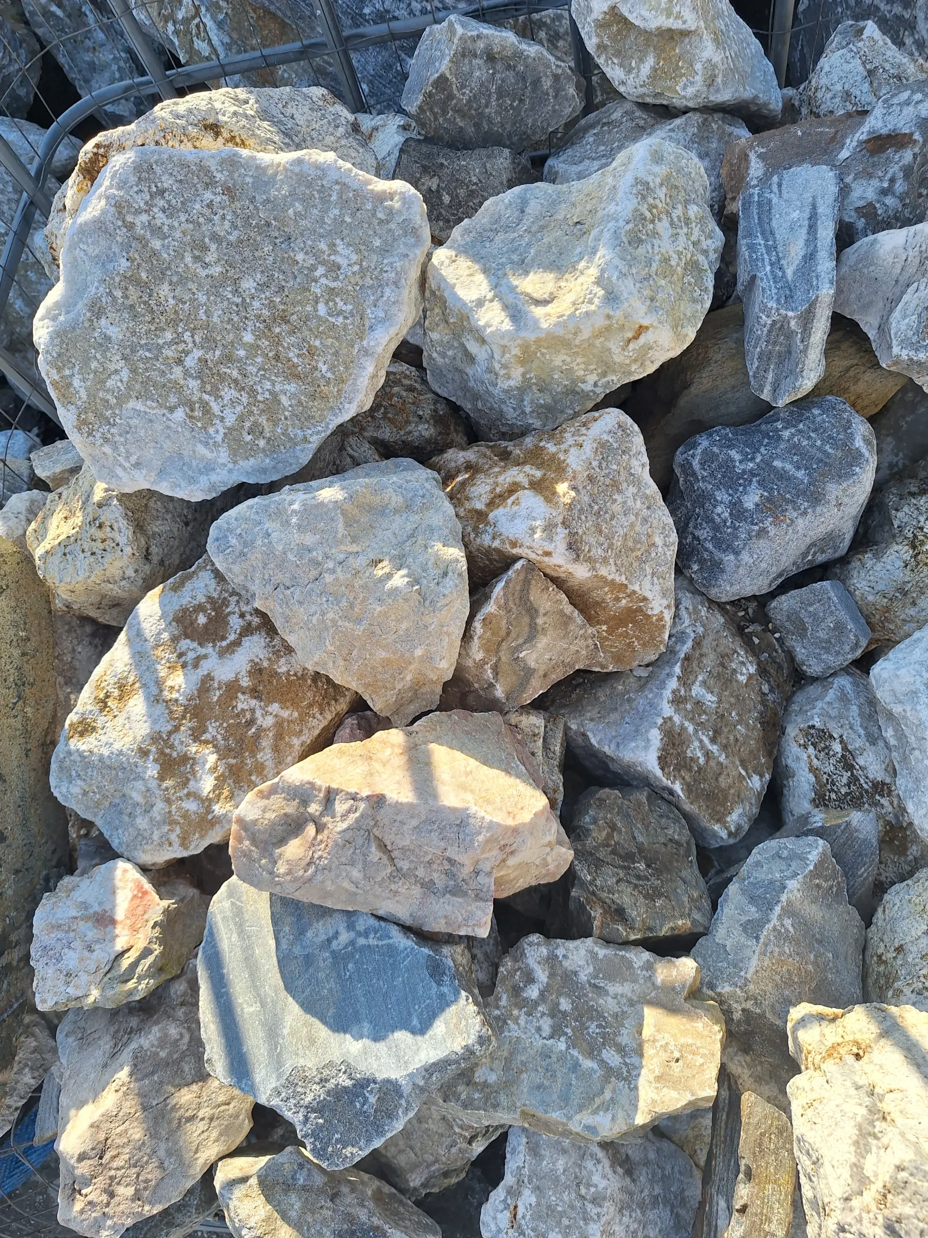 Stos jasnych nieregularnych kamieni dolomitowych do gabionów