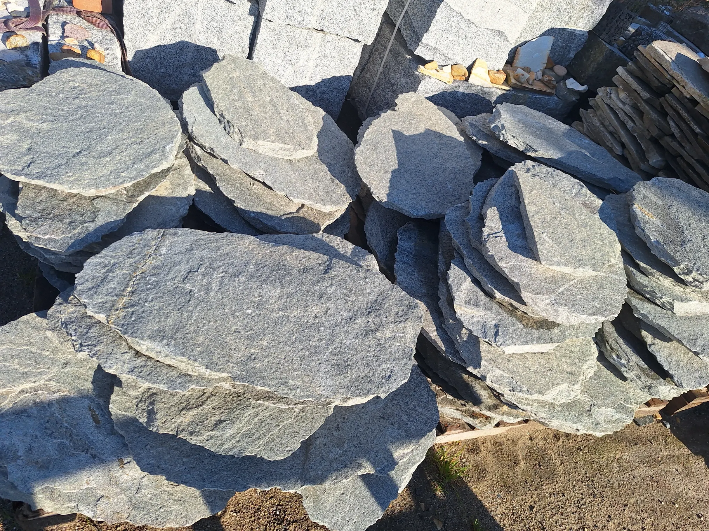 Stosy okrągłych płaskich płyt bazaltowych na paletach