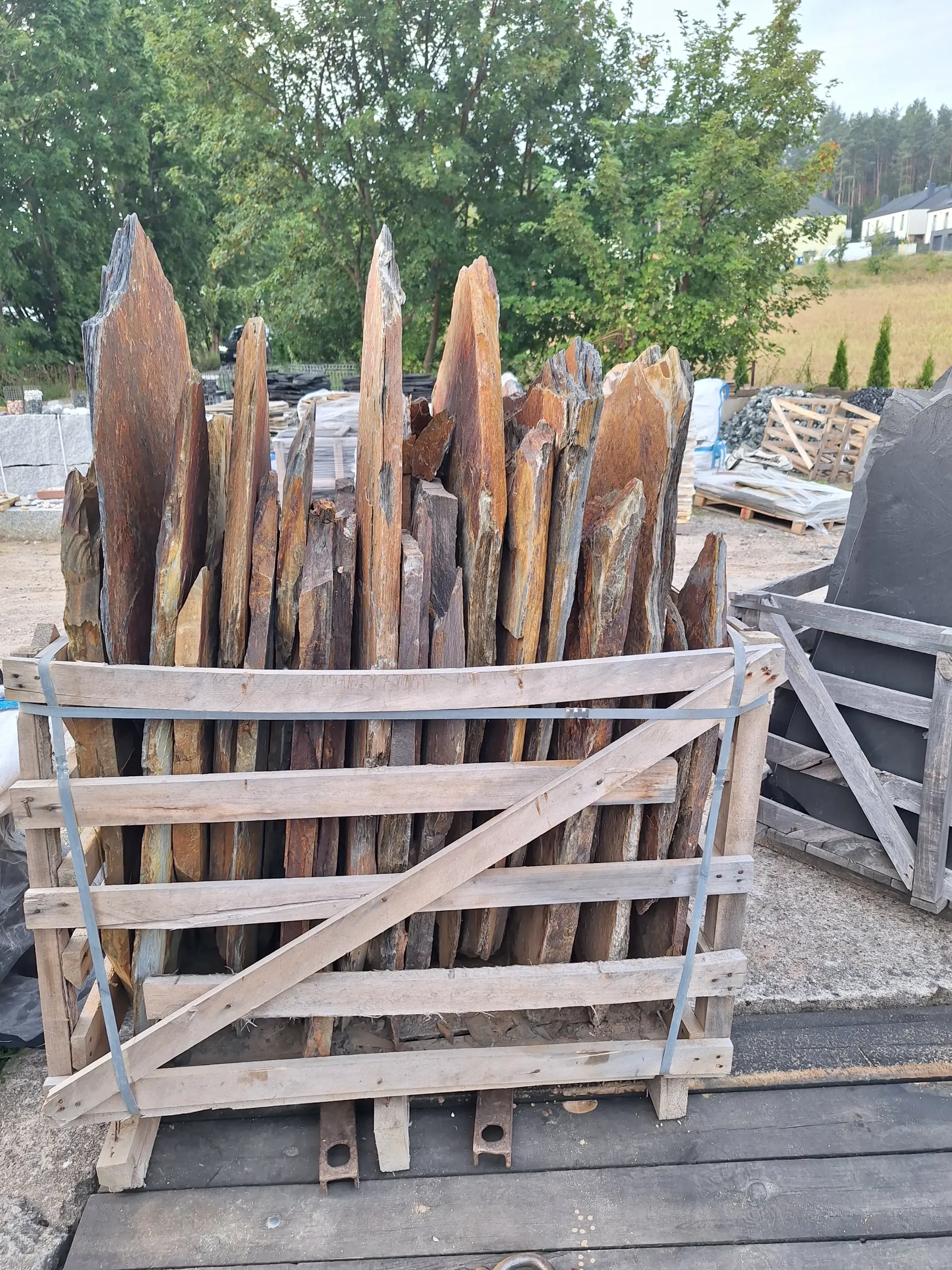 Łupane płaskie kamienie ozdobne w drewnianej skrzyni, gotowe do montażu elewacji lub ogrodzeń