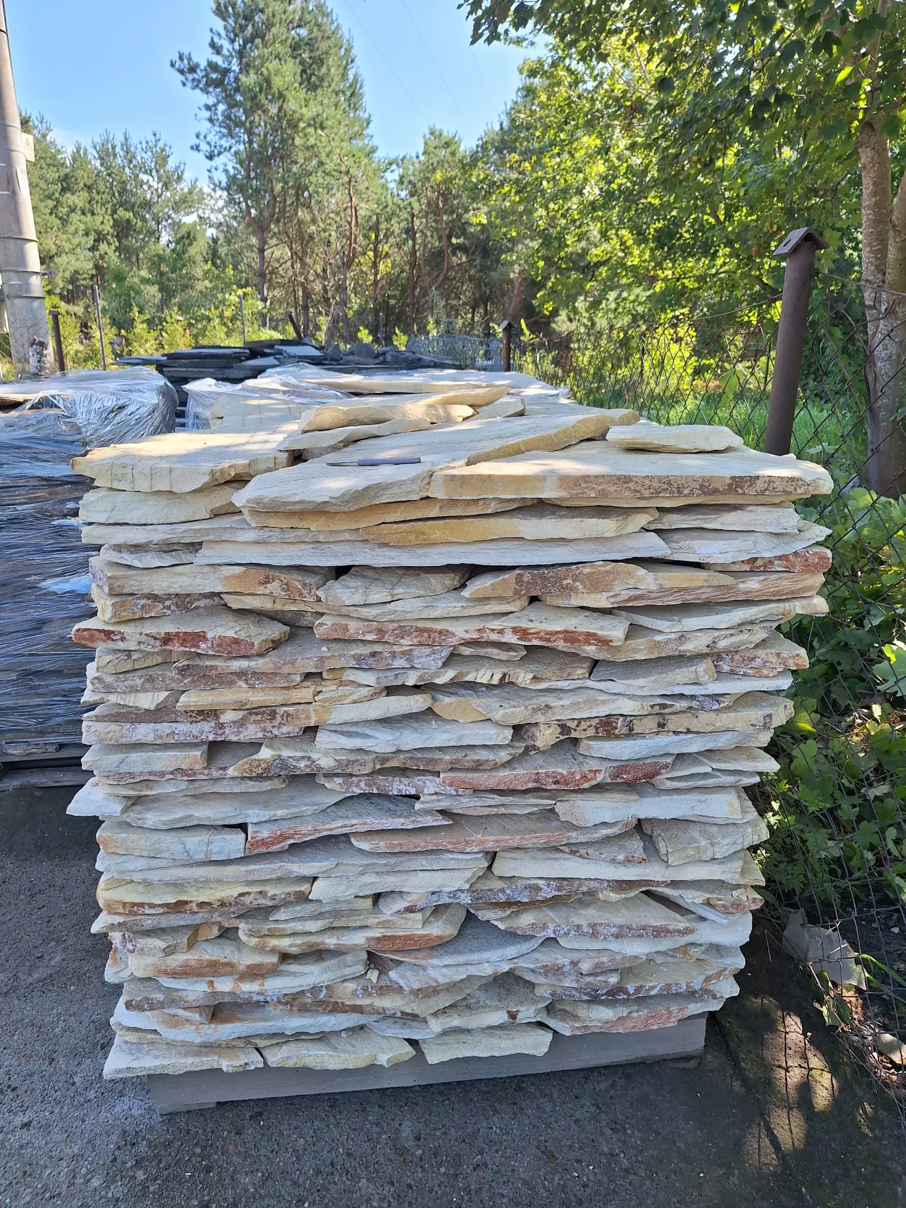 Stos nieregularnych płaskich płyt z dolomitu na palecie do wykończeń elewacji