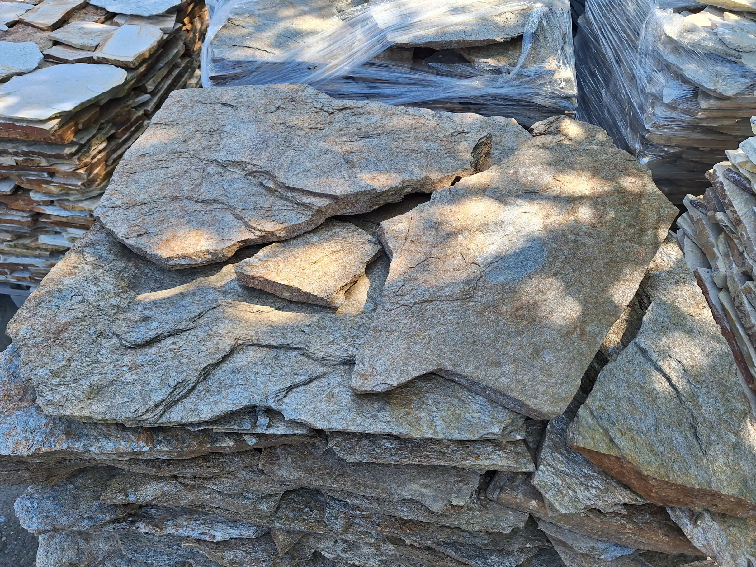 Stos płaskich, łupanych płyt z dolomitu przygotowanych do montażu