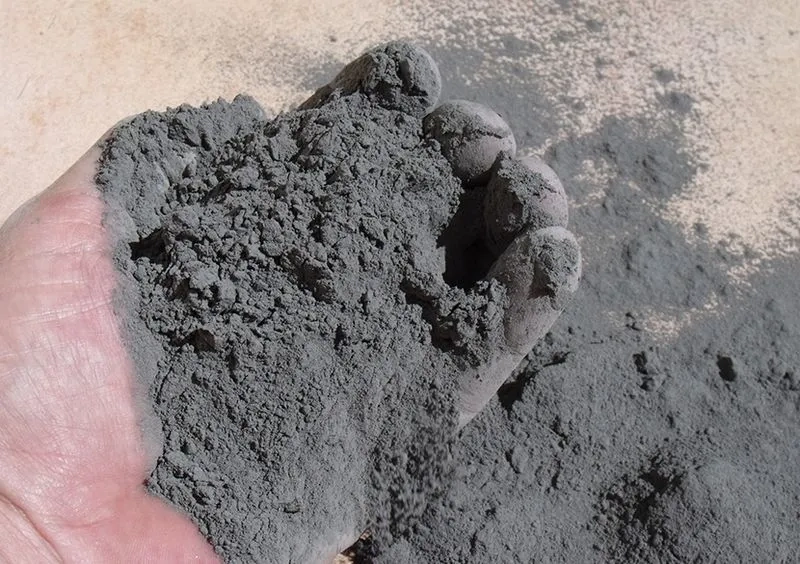Dłoń trzymająca szarą mączkę bazaltową